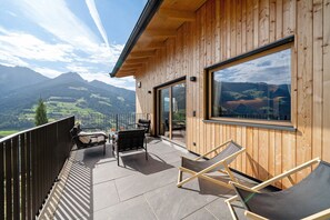 Una cabaña de madera con balcón, mobiliario exterior y vistas a la montaña.