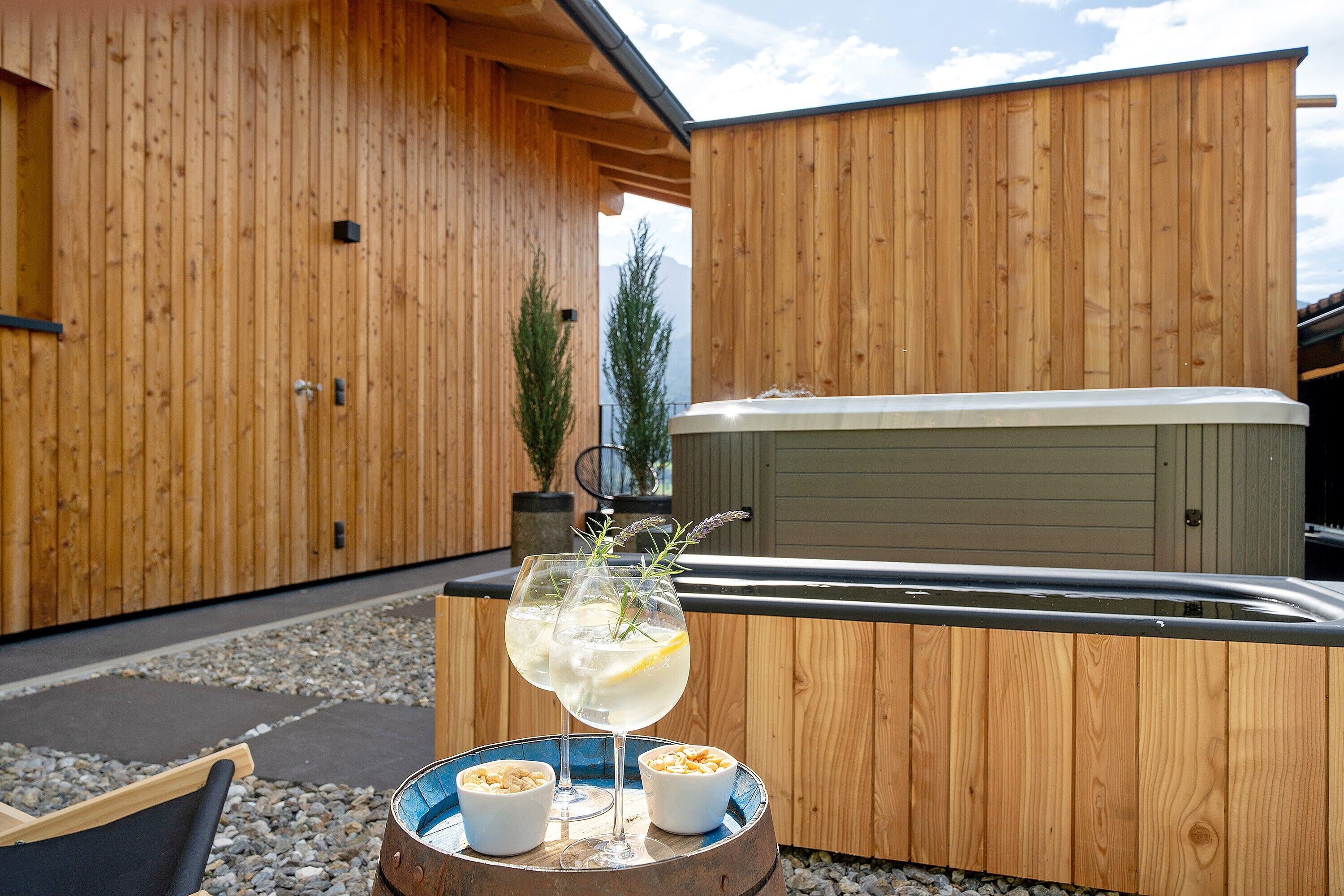 A wooden exterior wall, a hot tub, and two drinks on a table.