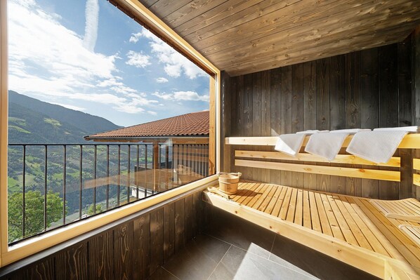 Un sauna en bois offrant une vue sur les montagnes grâce à une grande fenêtre.
