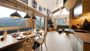 Une cuisine moderne avec un coin repas, de grandes fenêtres et une vue sur les montagnes.