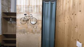 A room with a wooden wall, a blue curtain, and a bicycle mounted on the wall.