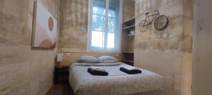 Une petite pièce étroite, avec un lit, une fenêtre et un vélo fixé au mur.