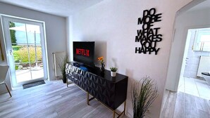 Una sala de estar moderna con un mueble de entretenimiento negro, un televisor de pantalla plana y un cuadro motivacional en la pared.