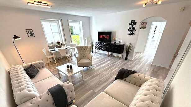 Una sala de estar moderna con un sofá, televisor y comedor.