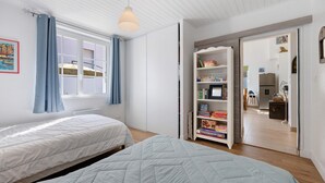 Une chambre avec deux lits, une armoire et une bibliothèque.