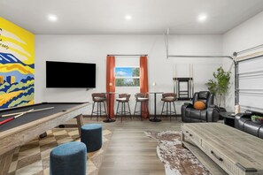 A modern living room with a pool table, bar stools, a leather sofa, and a TV mounted on the wall. - The Boise Rec Retreat-theater, pool table, arcade (Boise)