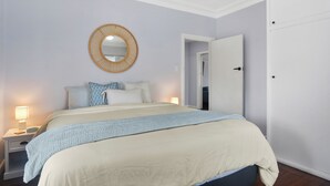 Un dormitorio con cama, lámparas de noche, un espejo redondo y una puerta.