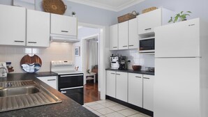 Una cocina moderna con armarios blancos, un lavamanos de acero inoxidable, un microondas y un refrigerador.