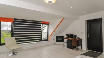 A modern room with a large window, a desk with a computer, a chair, and a bed.