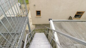 A metal staircase with a handrail leading to a building with a beige exterior. - The Nest (Glastonbury)