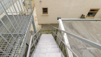 Una escalera metálica con barandilla que conduce a un edificio de fachada color beige.