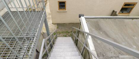 A metal staircase with a handrail leading to a building with a beige exterior.