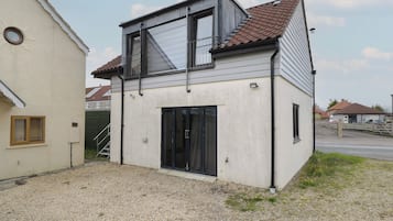 Una casa de dos pisos con balcón, garaje y entrada de grava.