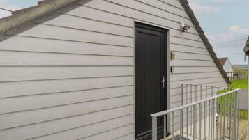A small, single-story building with a dark door and a metal railing.