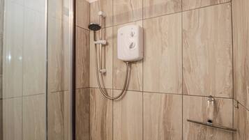 A shower with a handheld showerhead, a wall-mounted control panel, and a glass door.