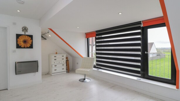 A modern room with a large window, a radiator, a white dresser, and a chair. - The Nest (Glastonbury)