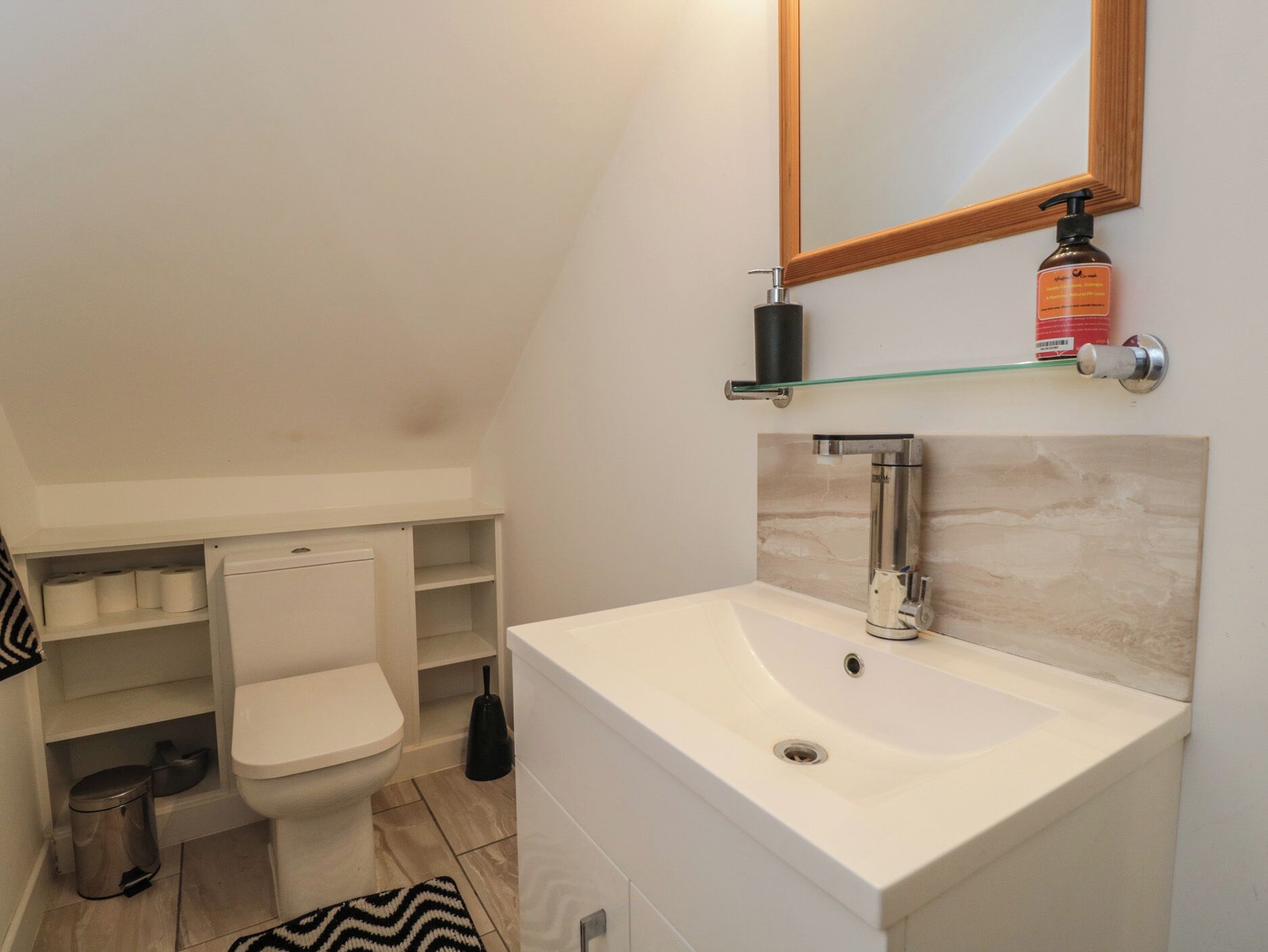 A modern bathroom with a toilet, sink, and mirror.