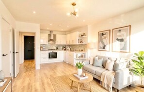 A modern apartment with an open-plan kitchen, a living area with a sofa, and a dining space. - Apartment Sleeps 2 With Parking (Luton)