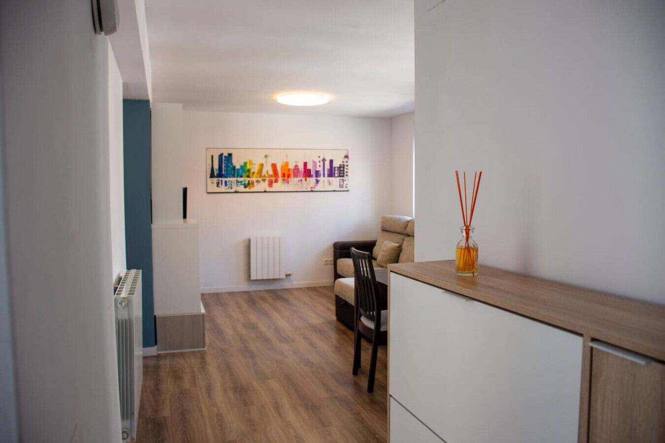 A modern living room with a sofa, a dining table, and a kitchen area with cabinets.