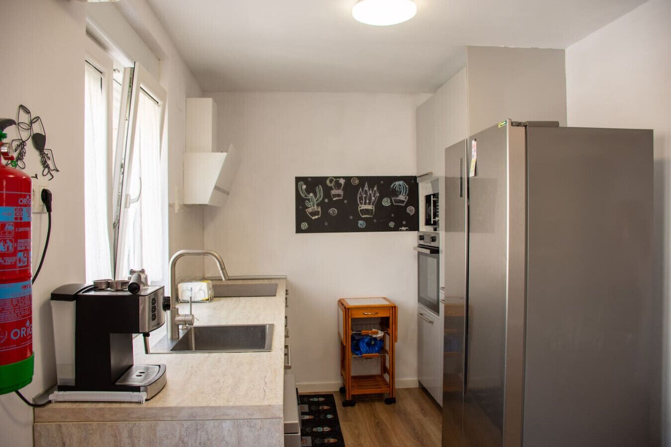 Eine kleine Küche mit Spüle, Mikrowelle, Backofen und Kühlschrank.