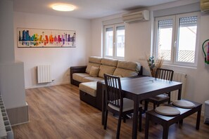 Ein modernes Wohnzimmer mit Sofa, Esstisch, Stühlen und einem Stadtbild.