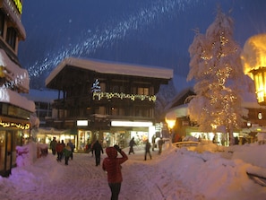 A building with a snow-covered roof and a Christmas tree with lights.