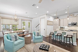 A spacious living area with a dining table, two sofas, a coffee table, and a kitchen with a bar. - Sandgrass Sanctuary | 30A | Golf Cart, Bikes | Sleeps 11 (Santa Rosa Beach)