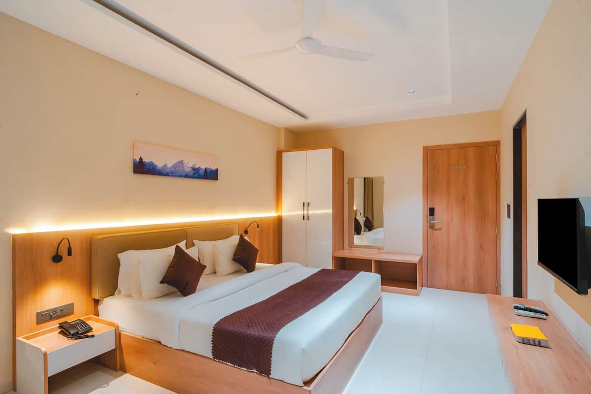 A modern hotel room with a bed, bedside table, nightstand, and a television.
