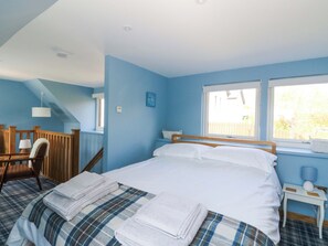 A bedroom with a bed, a chair, a window, and a small table.
