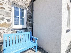 A blue bench outside a stone building with a window. - Post Cottage (Arisaig)
