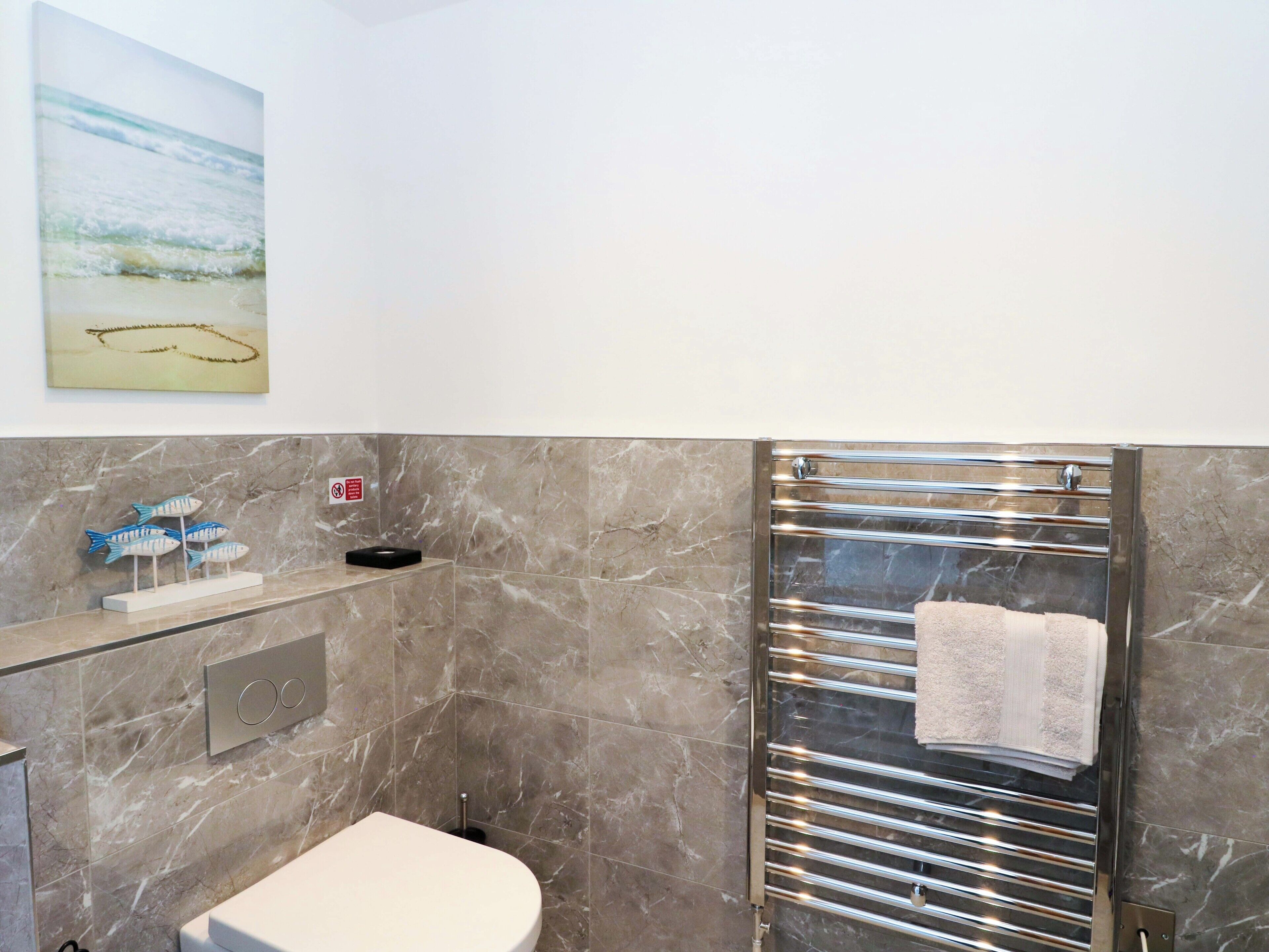 A bathroom with a marble floor, a toilet, a shower with a glass door, and a towel rack.