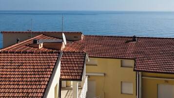 Un bâtiment situé sur la côte, avec des toits recouverts de tuiles en terre cuite et une vue sur la mer.