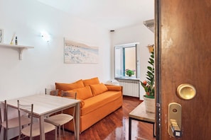 Een moderne woonkamer met een houten tafel, een oranje bank en een raam met uitzicht.