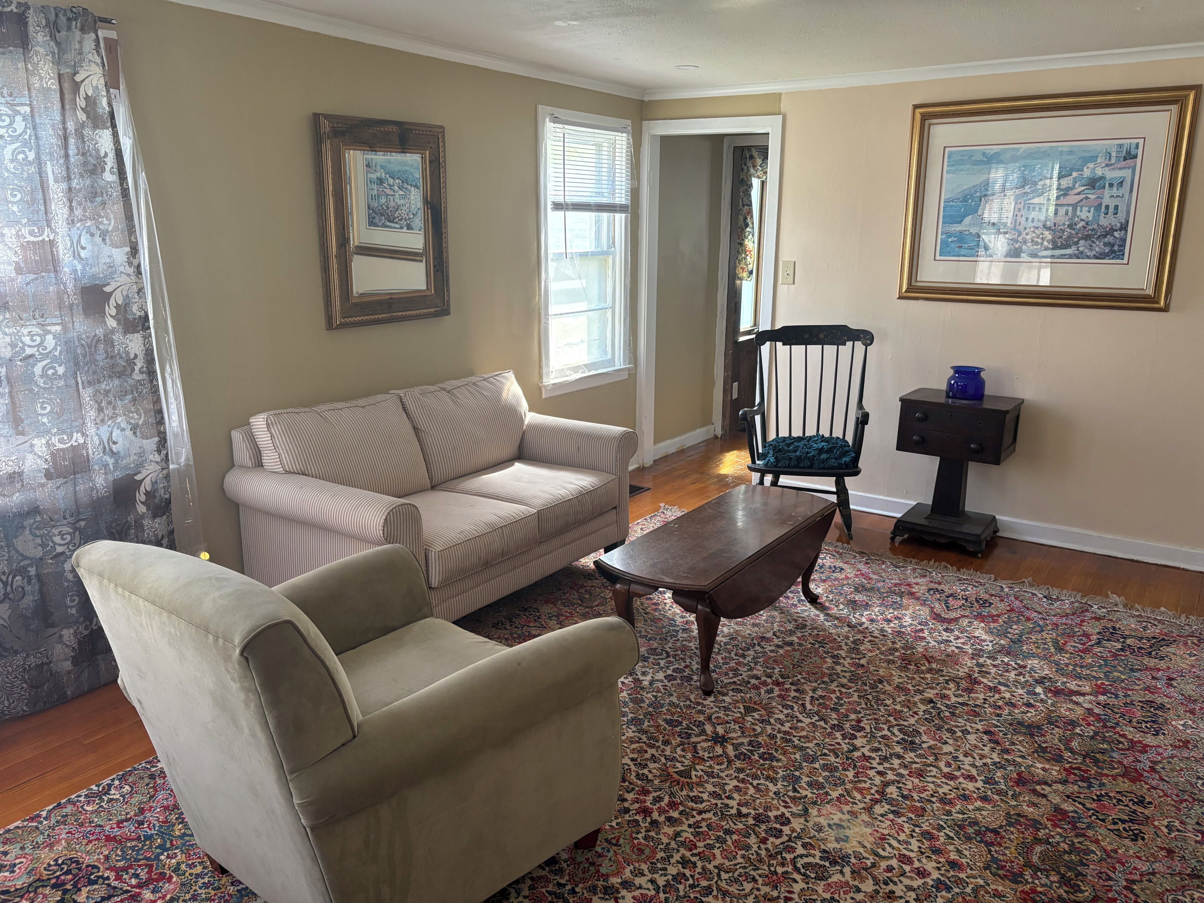 A living room with a sofa, armchair, wooden coffee table, and a patterned rug.