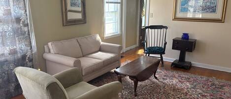 A living room with a sofa, armchair, wooden coffee table, and a patterned rug.