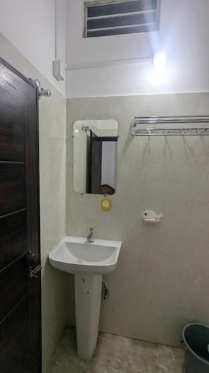 A small bathroom with a white sink, a mirror, a towel rack, and a shower curtain. - Kamakhya Homestay by Bonoriya (Guwahati)