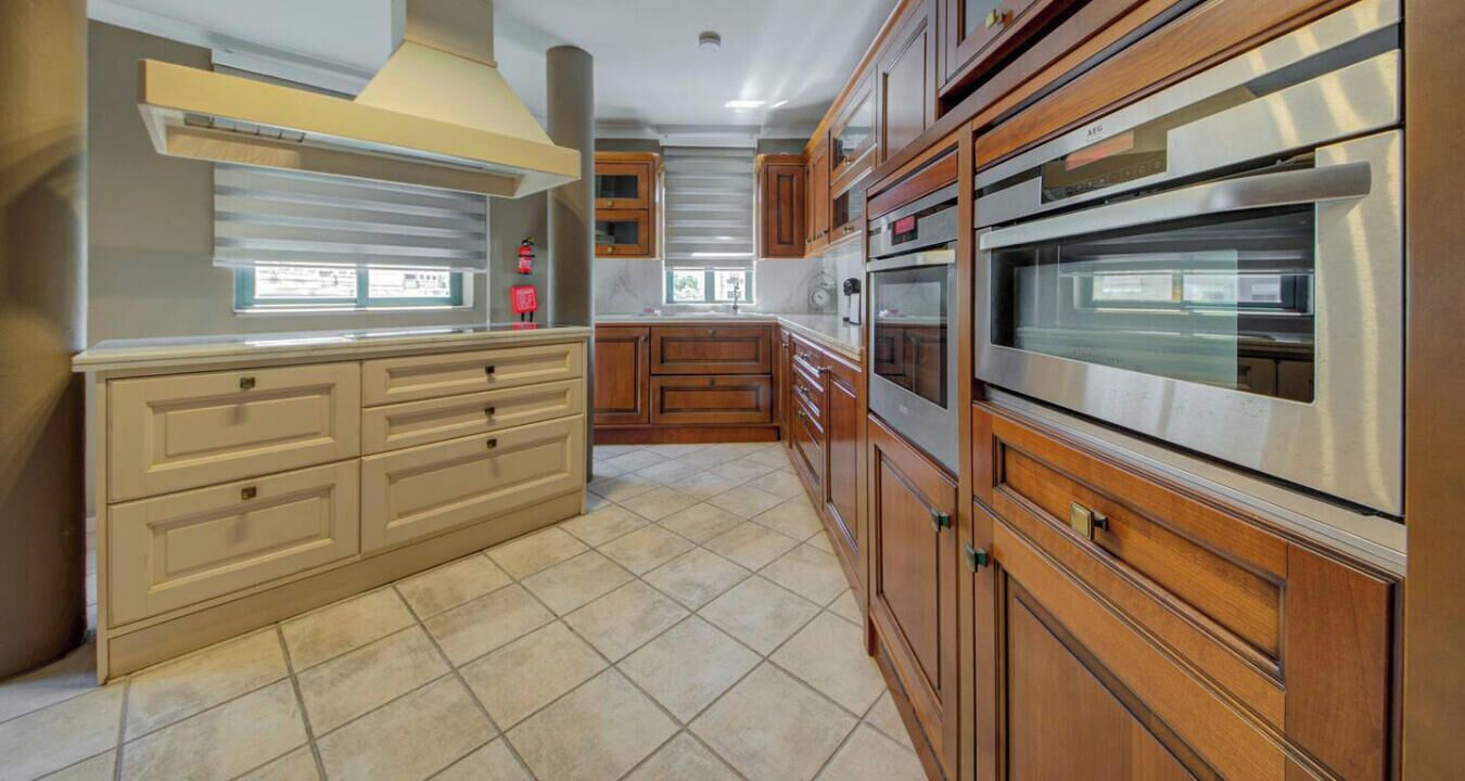 A kitchen with wooden cabinets, stainless steel appliances, and a tiled floor.
