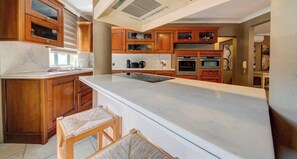 A kitchen with wooden cabinets, a marble countertop, and a built-in oven. - Premium 3BR Home in Swieqi Near St Julians & Shops (Swieqi)