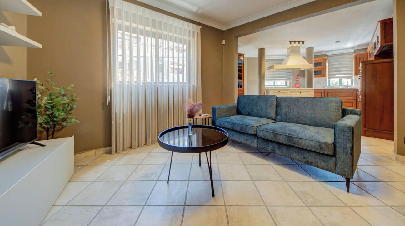 Een woonkamer met een bank, een salontafel, een televisie en een plant.