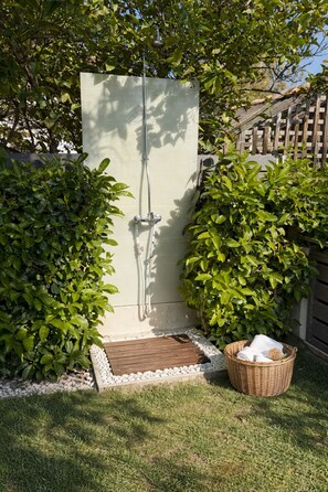 A small, enclosed outdoor shower area with a wooden deck and surrounding greenery. - Villa Paionia/ Heated Pool/ Sea View/ Private Resort (Anavissos)