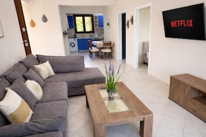 A living room with a sofa, coffee table, and a TV displaying 'NETFLIX'. - Villa Paionia/ Heated Pool/ Sea View/ Private Resort (Anavissos)