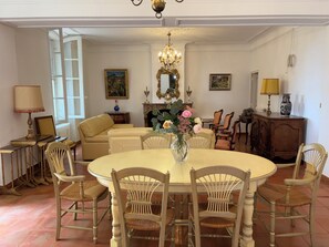 A dining room with a round table, chairs, a chandelier, and a fireplace. - Maison de Famille du XIX° siècle - Property in Terre de PROVENCE- swimming pool (Saint-Chamas)