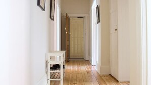 Un couloir doté d’un plancher en bois, de murs blancs et d’un banc blanc.
