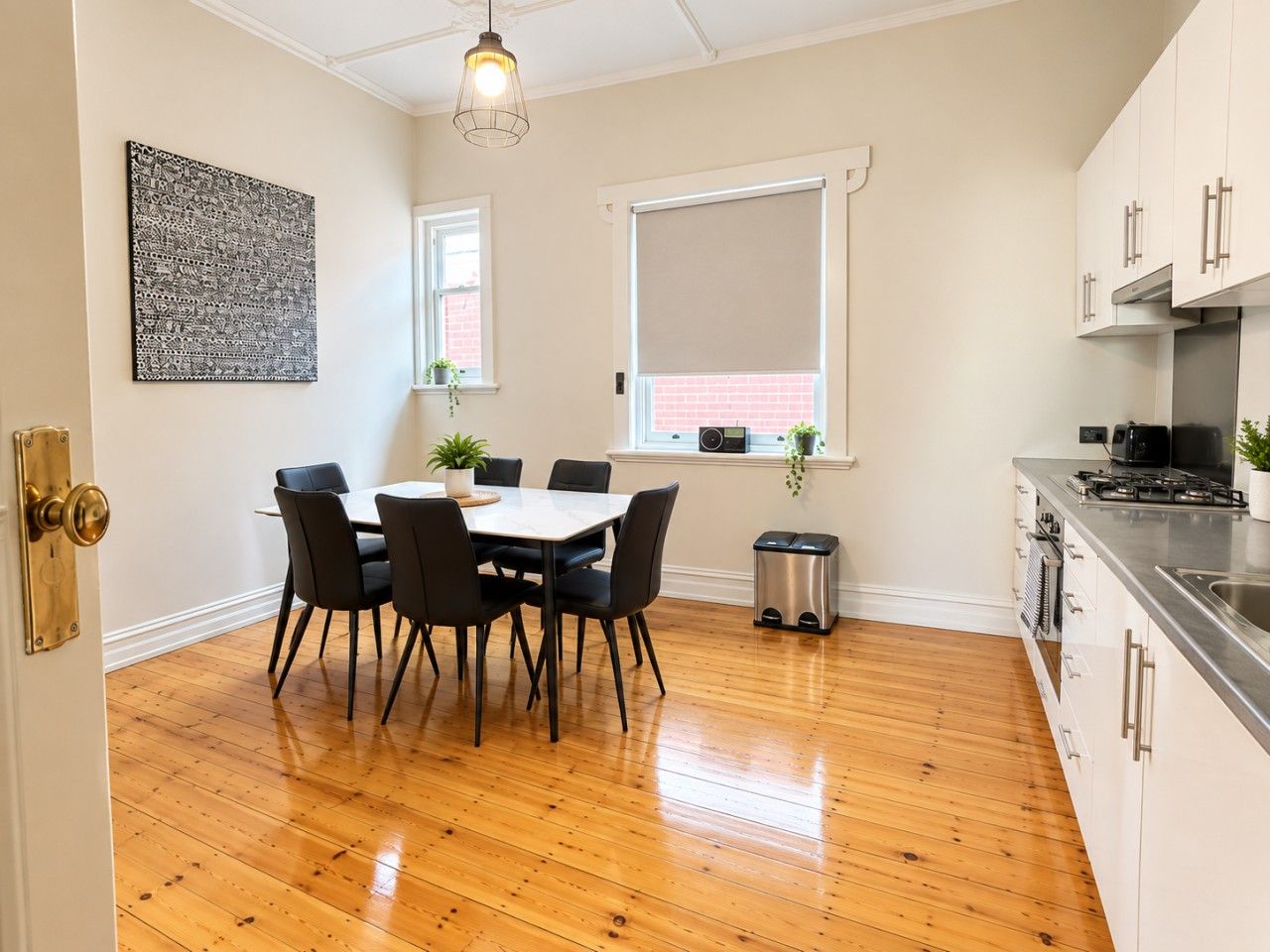A modern kitchen with white cabinets, a stainless steel countertop, and a built-in stove.
