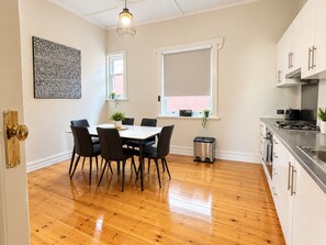 A modern kitchen with white cabinets, a stainless steel countertop, and a built-in stove. - Ocean-View Apartment in Glenelg | Walk to Beach (Glenelg)