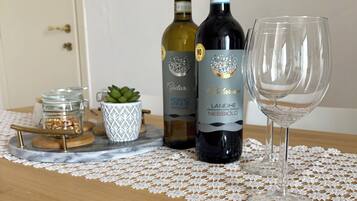A table with two wine bottles and a glass on a lace doily.