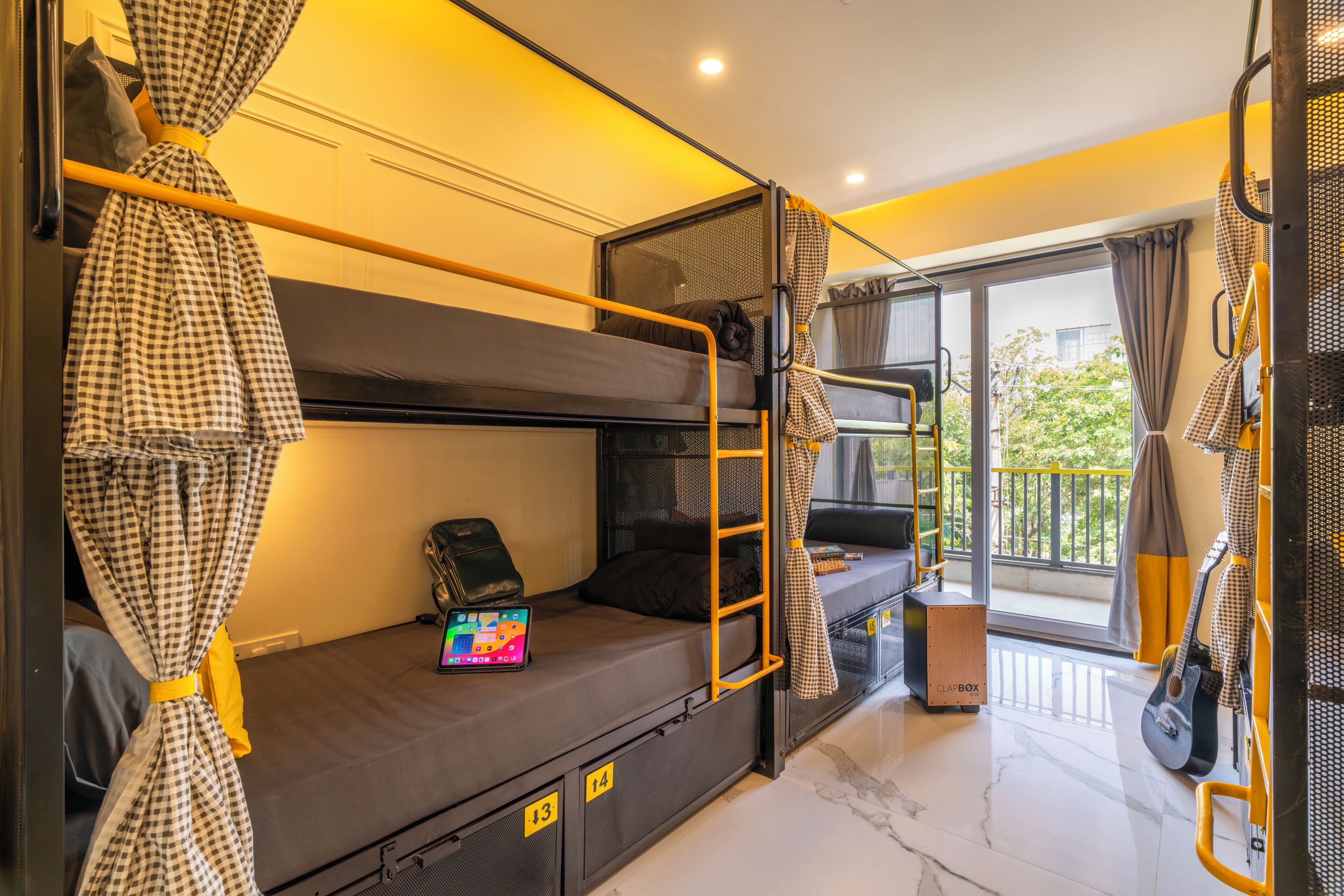 A bunk bed room with a laptop, a suitcase, and a speaker on the lower bunk.