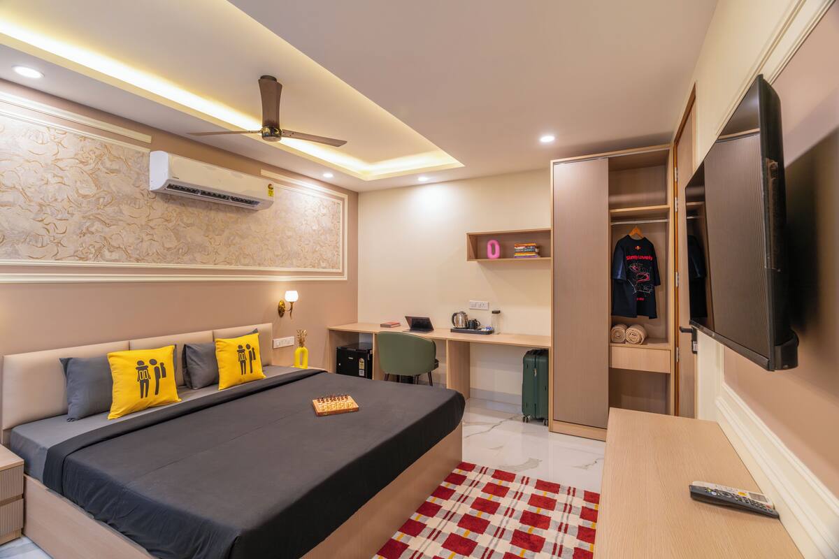 A modern bedroom with a bed, desk, TV, and wardrobe.