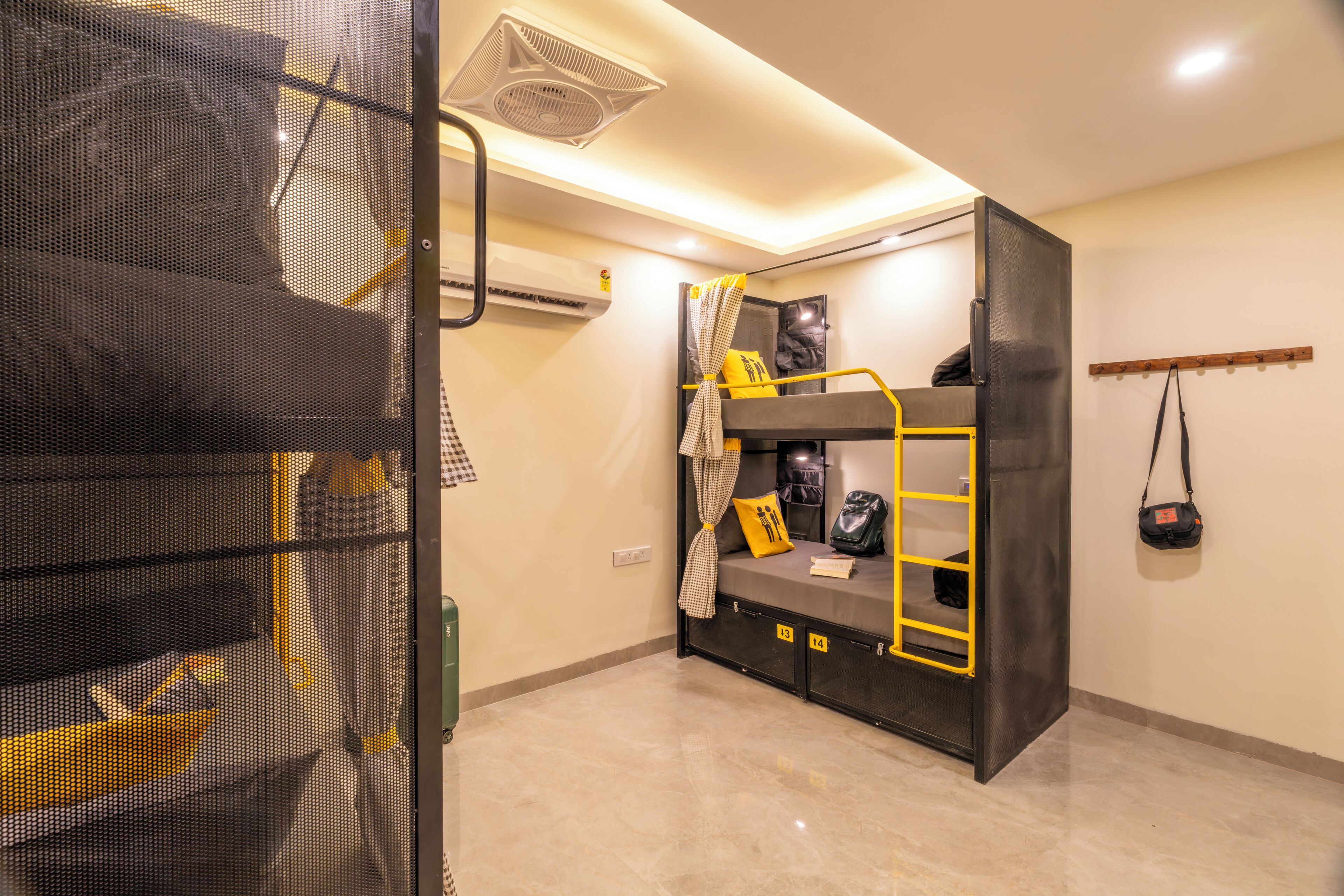 A bunk bed room with a ceiling fan, a coat rack, and a wall-mounted air conditioner.