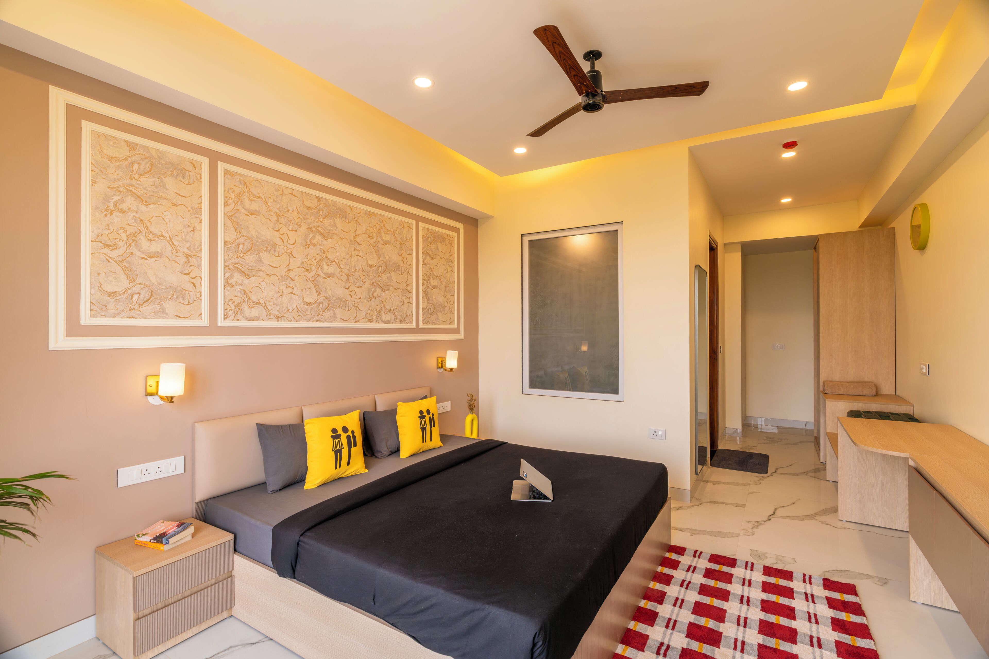 Une chambre à coucher moderne, avec un lit, des tables de chevet, un ventilateur de plafond et une grande œuvre d’art accrochée au mur.